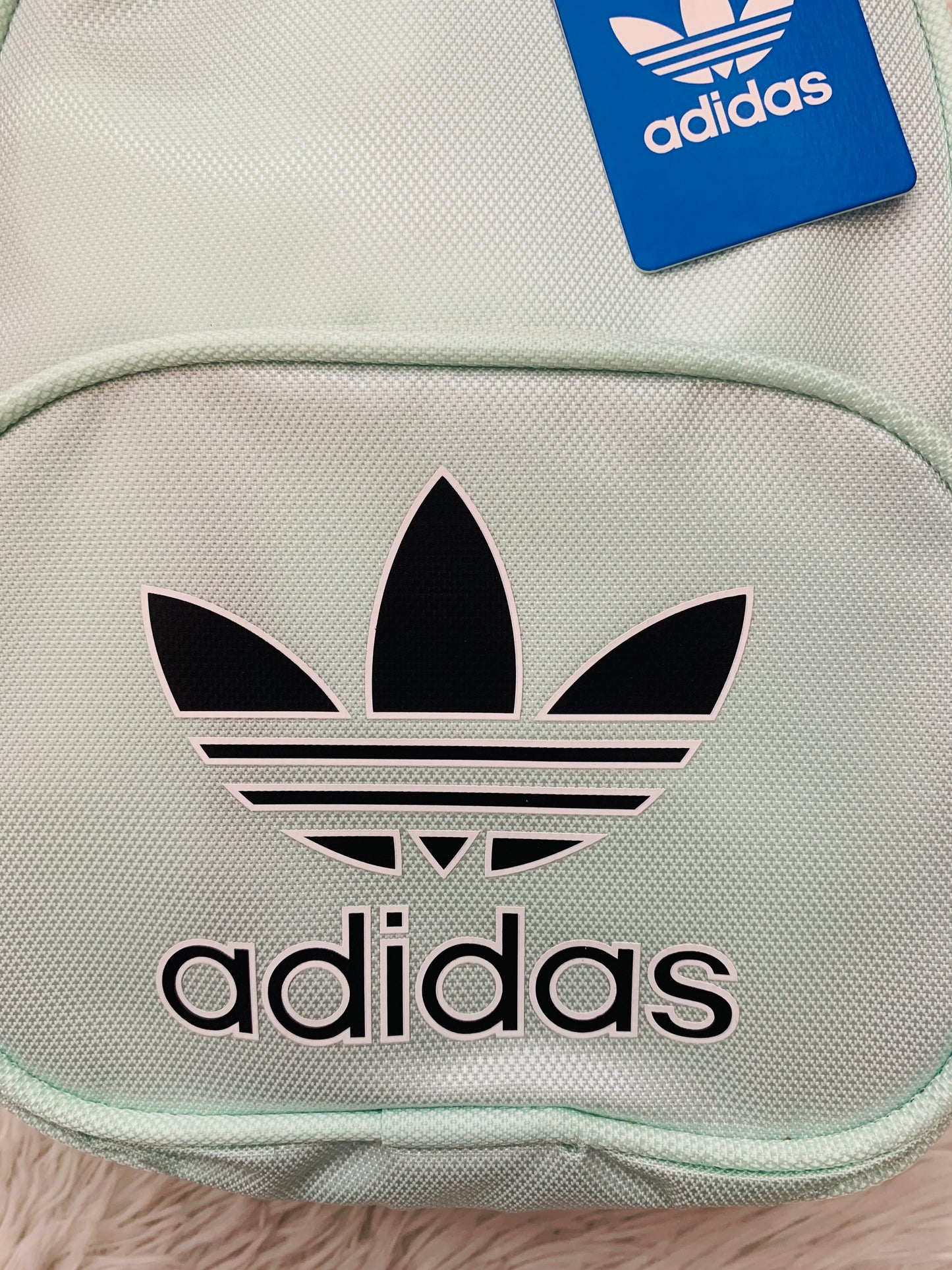 Mochila Adidas original en color verde turquesa con letras al frente ADIDAS y logo tipo en color blanco, negro bolsillo en frente