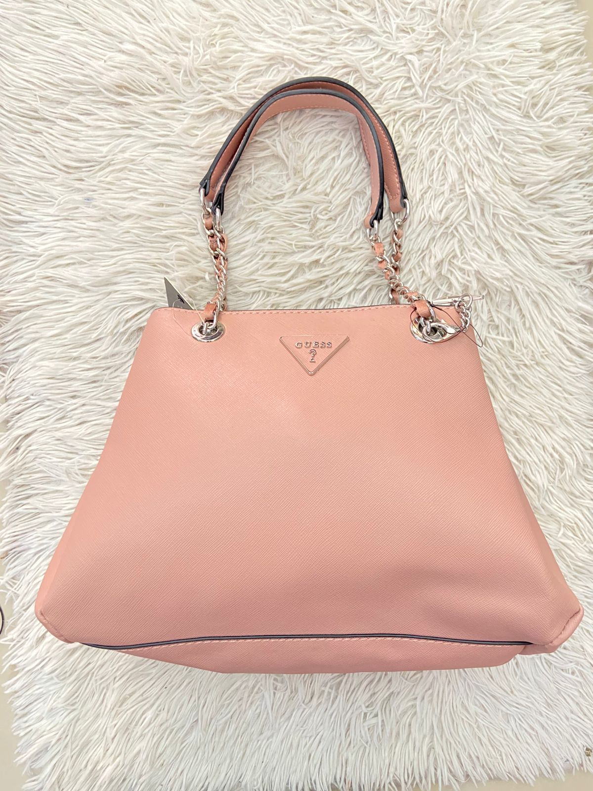 Cartera GUESS Original, color rosado pastel con logo en el centro y asas con cadena plateada.