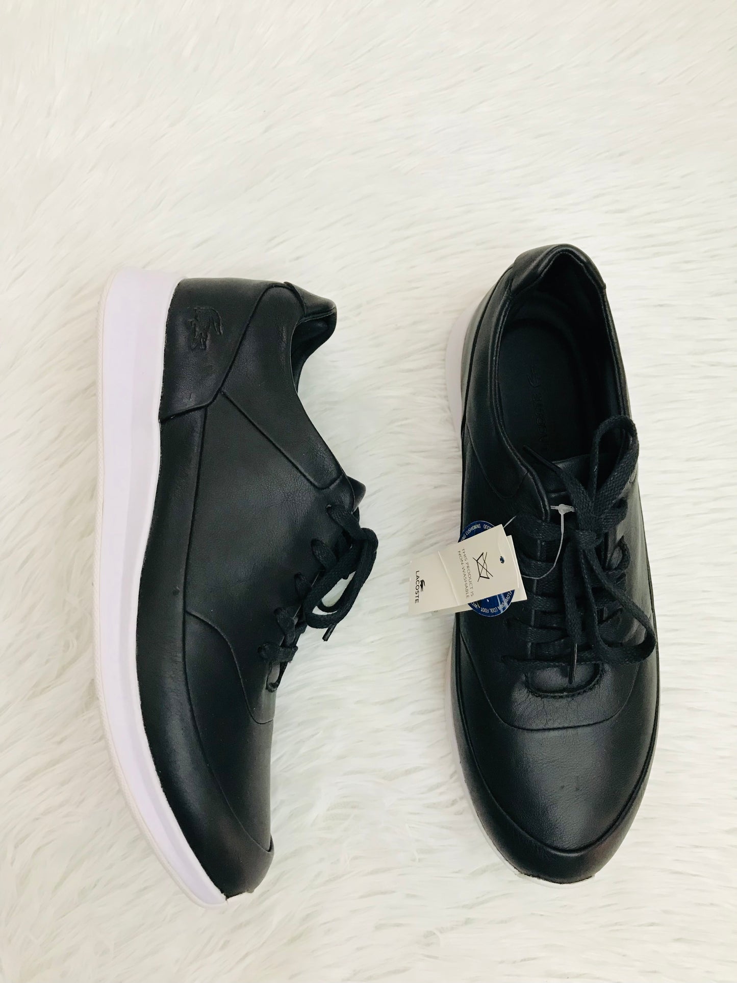 Zapato Lacoste original, color negro con parte de abajo blanca, logotipo pequeño de la marca en un lado en color negro poco visible.
