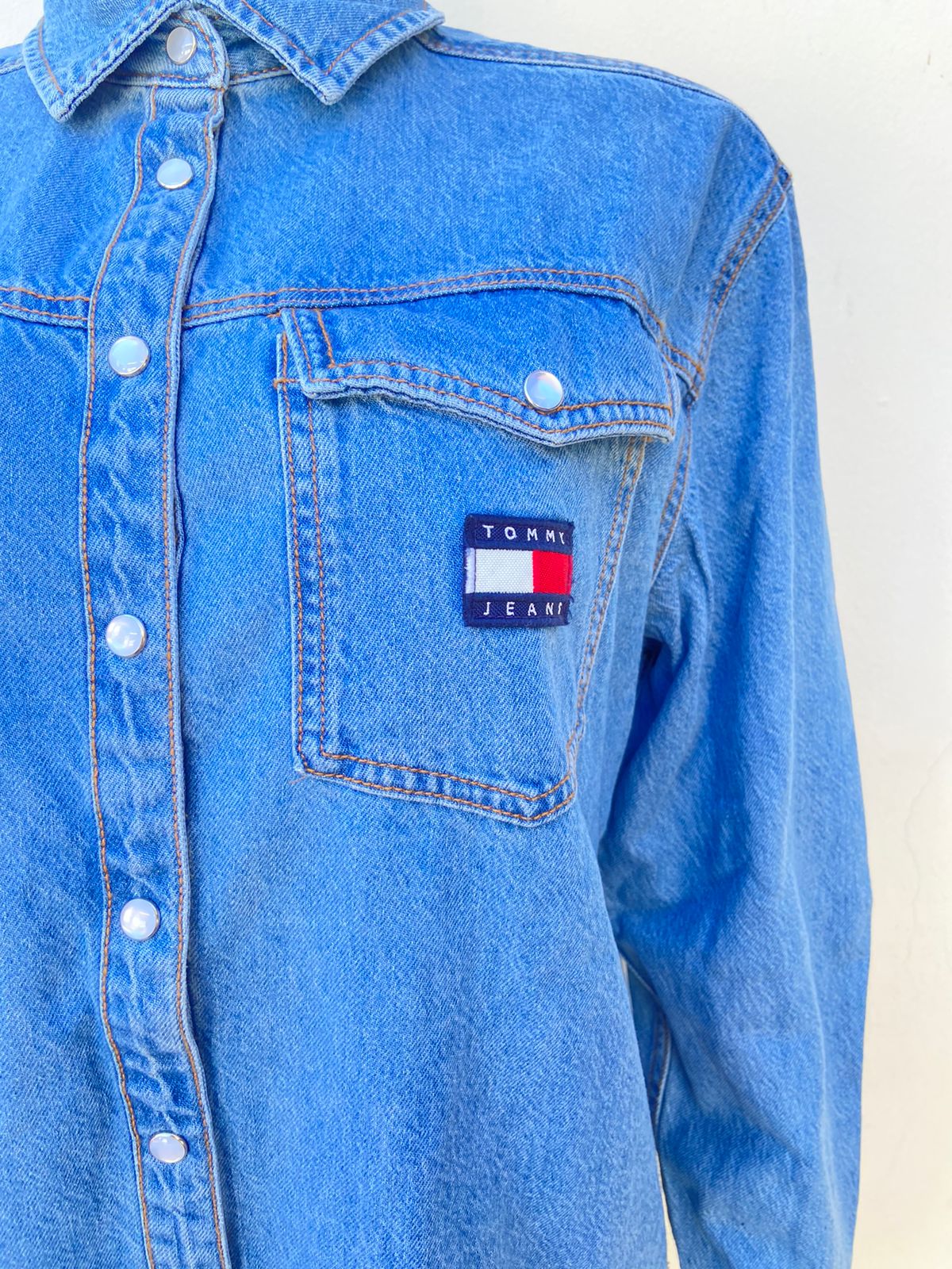 Vestido Tommy Hilfiger original jean en color azul claro (blusón) con dos bolsillos delante con pequeño logo con letras TOMMY HILFIGER en color blanco y azul botones blanco y bolsillos a los lados, manga larga.
