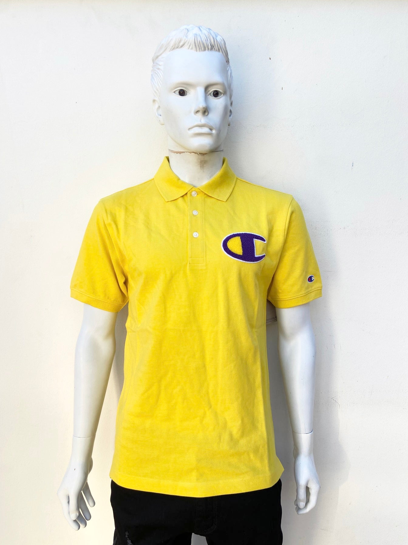 Polocher Champion original de color amarillo con logo CHAMPION al frente en morado y amarillo y letras CHAMPION en color morado en la parte de atrás
