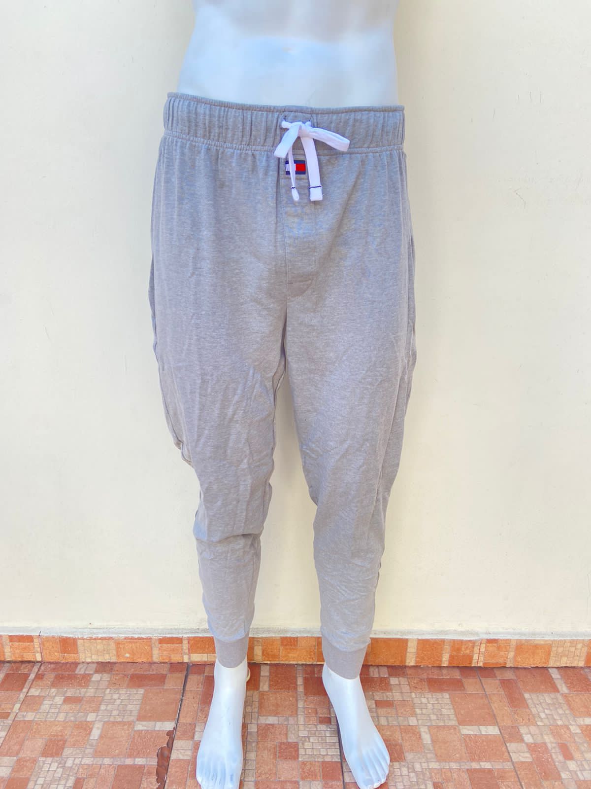 Pantalón/ Jogger Tommy Hilfiger original, gris claro con lazo ajustable en el centro de color blanco.