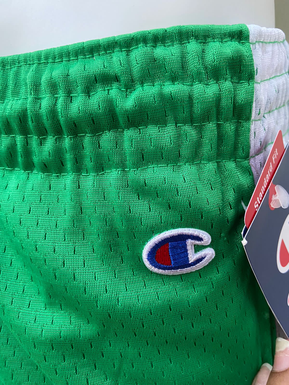 Bermuda Champion original, verde con líneas blancas alrededor y pequeño logotipo de la marca en un lado.