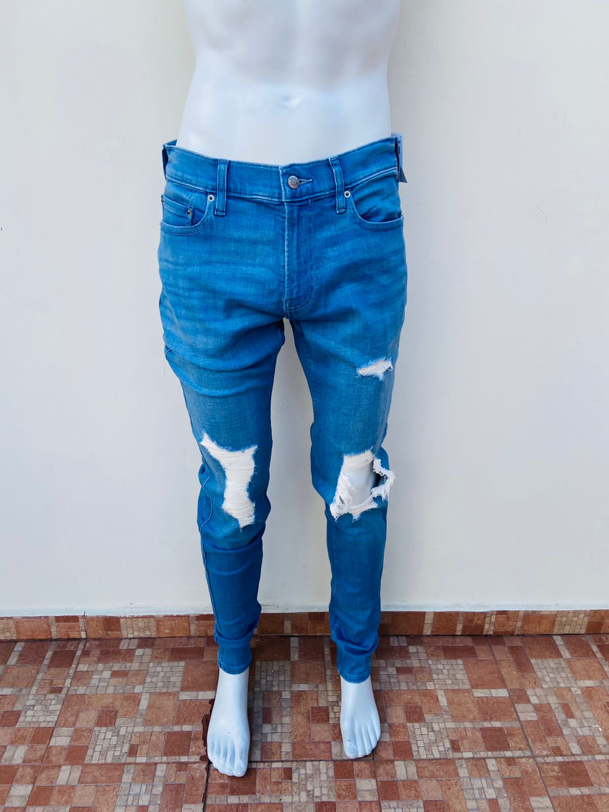 Pantalon jeans Hollister original azul claro con rasgados al frente y diseño de letra HOLLISTER CALIFORNIA en la parte de atrás con recuadro blanco ADVANCE STRETCH STACKED SKINNY