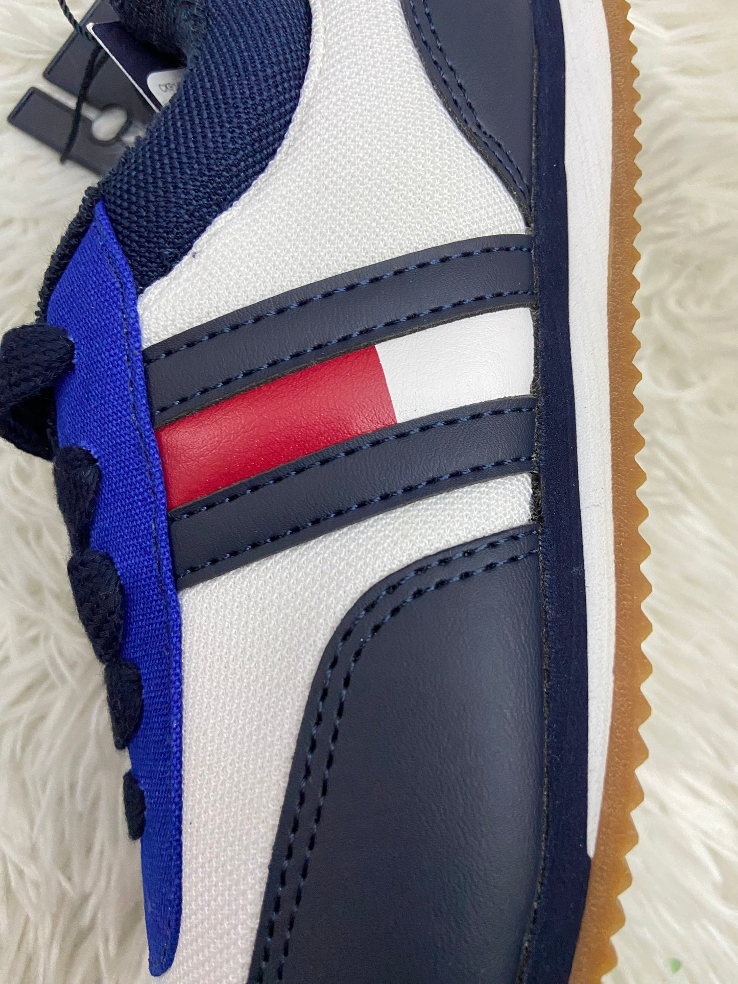 Tenis Tommy Hilfiger original, blanco con bordes azul marino, cordones azul marino, y logotipo de la marca en ambos lados.