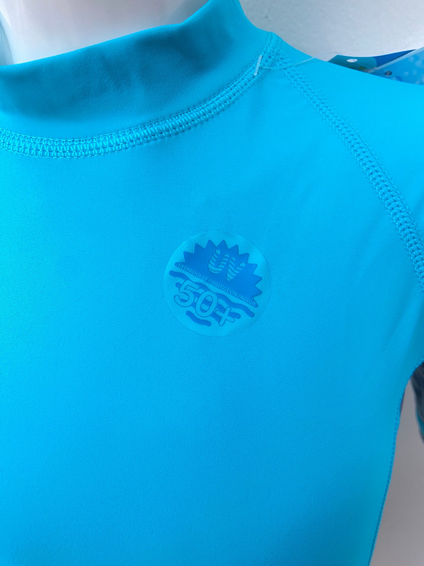 T-shirt de traje de baño Sporti original de color azul con raya a los lados en color gris oscuro con protección UV 50+ diseño de letra SPORTI en la parte de abajo en color plateado
