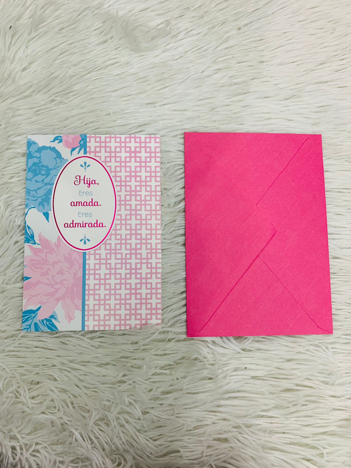 Tarjeta de felicitaciones blanca con disease flores rosas y azul y cuadrado en color rosado con letras HIJA ERES AMADA ERES ADMIRADA en la parte del frente y dedicatoria dentro